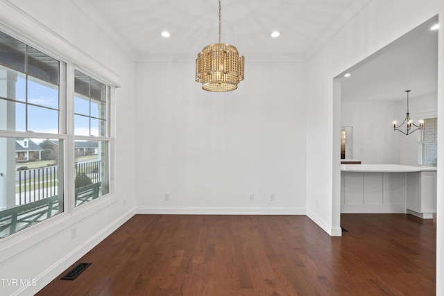 unfurnished dining area with a chandelier, dark hardwood / wood-style flooring, and crown molding