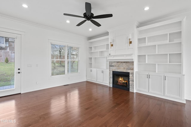 unfurnished living room featuring a fireplace, dark hardwood / wood-style flooring, a wealth of natural light, and ornamental molding