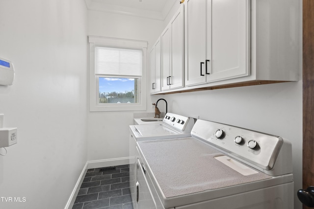 clothes washing area with separate washer and dryer, dark tile patterned floors, cabinets, and ornamental molding