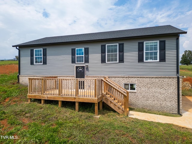 rear view of house featuring a wooden deck and a yard