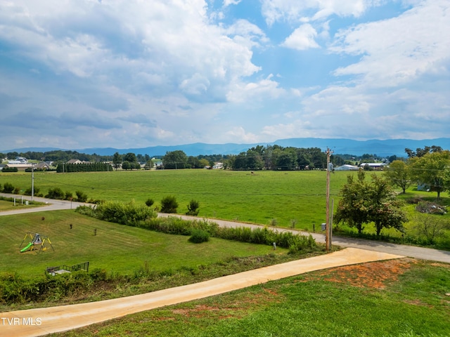 view of community featuring a rural view, a mountain view, a lawn, and a playground