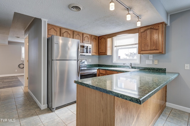 kitchen with kitchen peninsula, light tile patterned floors, stainless steel appliances, and sink