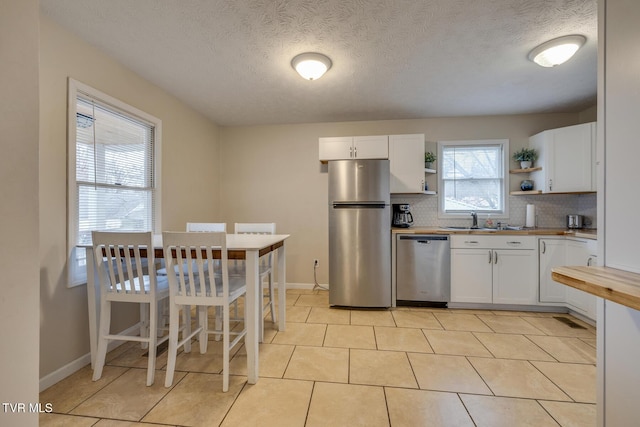 kitchen featuring decorative backsplash, white cabinetry, sink, and appliances with stainless steel finishes