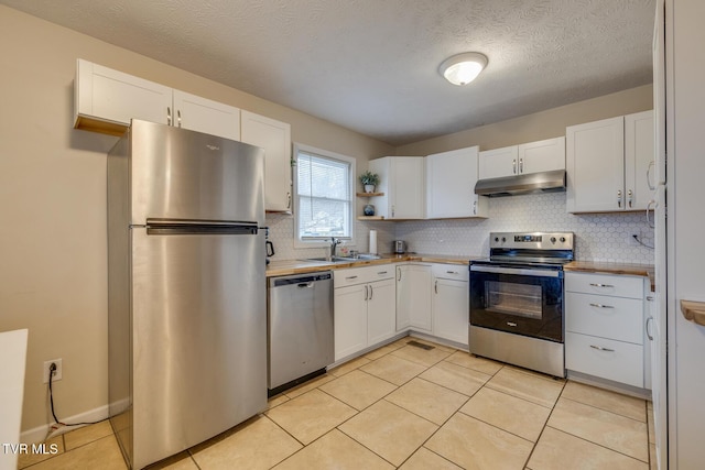 kitchen with sink, light tile patterned floors, a textured ceiling, white cabinetry, and stainless steel appliances