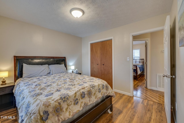 bedroom featuring wood-type flooring, a textured ceiling, and a closet