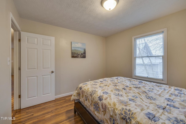 bedroom featuring a textured ceiling and dark hardwood / wood-style floors