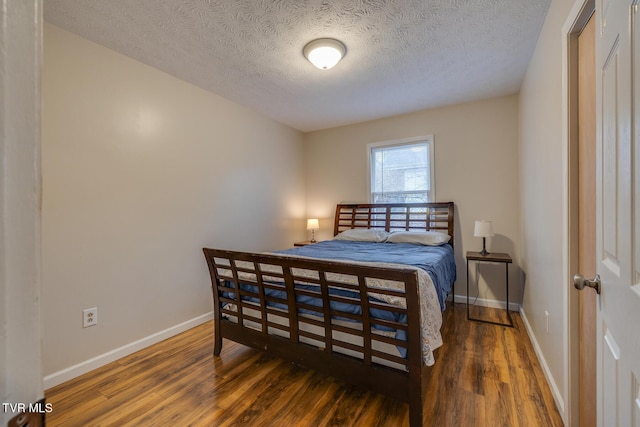 bedroom featuring a textured ceiling and dark hardwood / wood-style floors