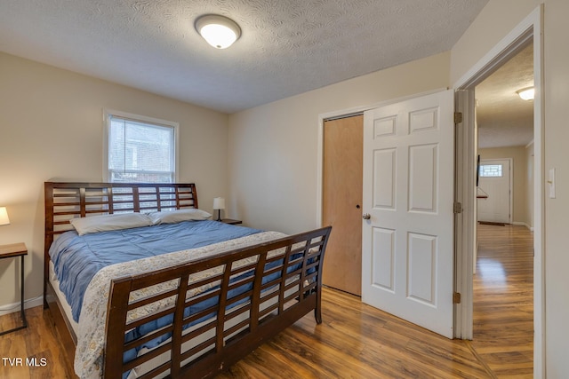 bedroom featuring dark hardwood / wood-style flooring, a textured ceiling, and a closet