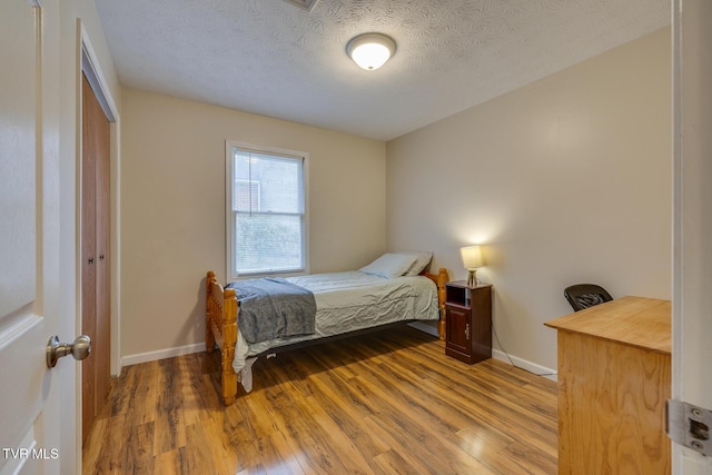 bedroom with a textured ceiling, hardwood / wood-style flooring, and a closet