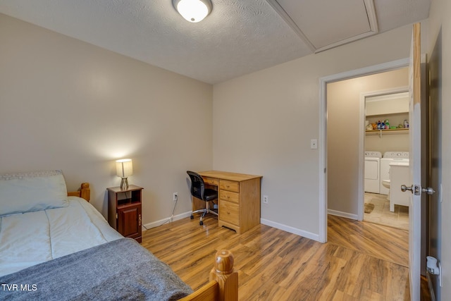 bedroom with a textured ceiling, light hardwood / wood-style floors, and washing machine and clothes dryer