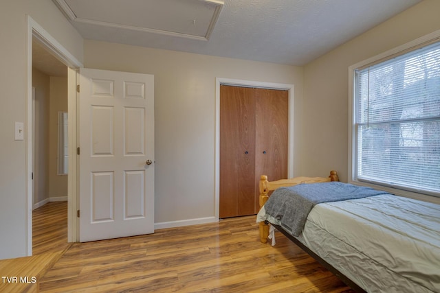 bedroom featuring a textured ceiling, light hardwood / wood-style flooring, and a closet