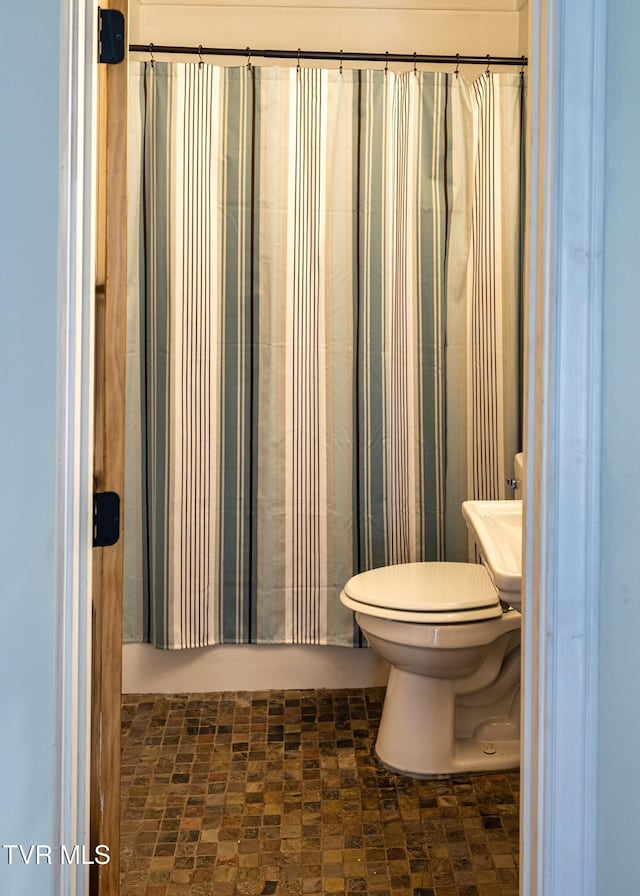 bathroom with a shower with shower curtain and toilet