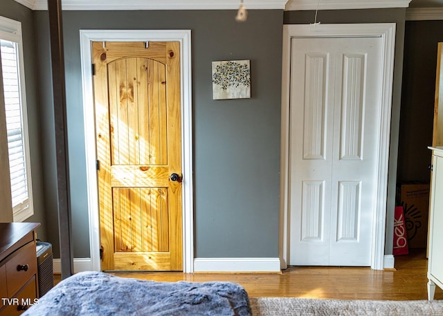 bedroom with multiple windows, crown molding, and hardwood / wood-style flooring