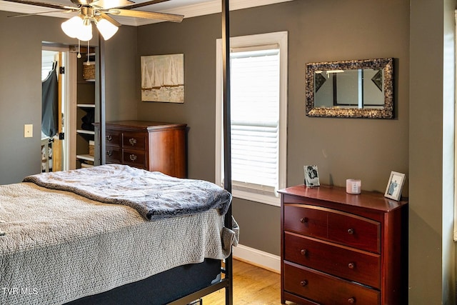 bedroom featuring ceiling fan, light wood-type flooring, crown molding, and multiple windows