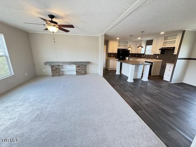 unfurnished living room with ceiling fan, dark hardwood / wood-style floors, and a textured ceiling