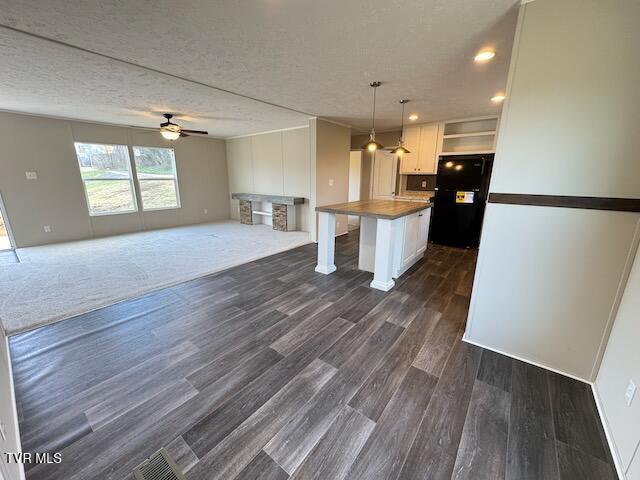 kitchen with black fridge, a breakfast bar, a kitchen island, white cabinetry, and hanging light fixtures