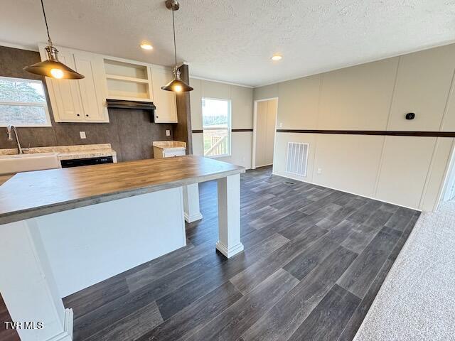 kitchen featuring a textured ceiling, sink, white cabinetry, hanging light fixtures, and butcher block counters