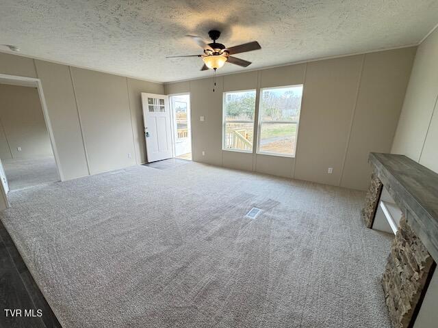 unfurnished living room featuring carpet flooring, ceiling fan, and a textured ceiling