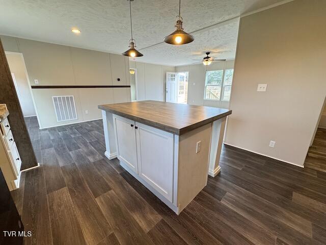 kitchen featuring wooden counters, ceiling fan, pendant lighting, white cabinets, and a center island