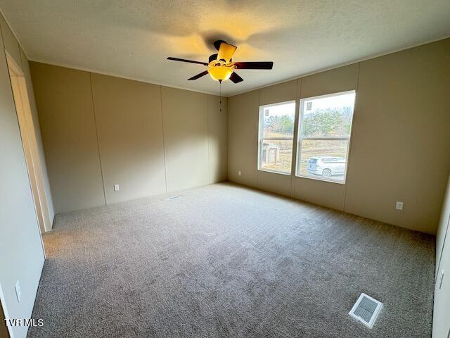 carpeted empty room featuring ceiling fan and a textured ceiling