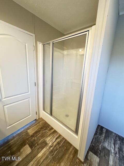 bathroom featuring wood-type flooring and an enclosed shower