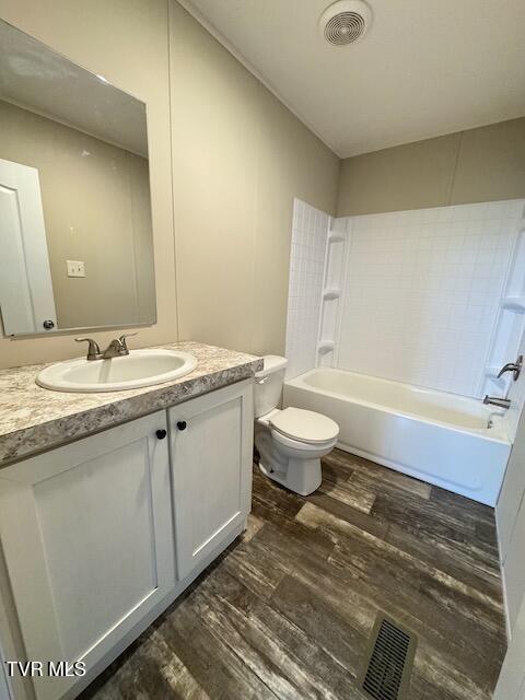 full bathroom with hardwood / wood-style flooring, vanity, toilet, and shower / bathing tub combination