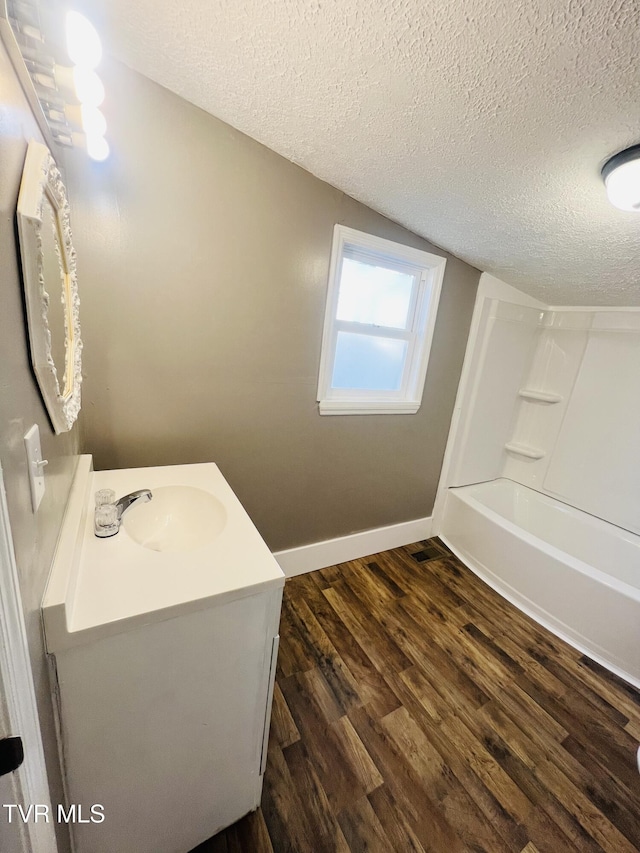 bathroom with hardwood / wood-style floors, vanity, shower / bath combination, and a textured ceiling