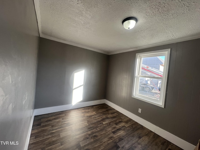 spare room with ornamental molding, a textured ceiling, wooden walls, and dark wood-type flooring