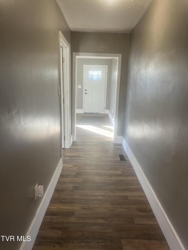 hallway with dark hardwood / wood-style floors and a textured ceiling