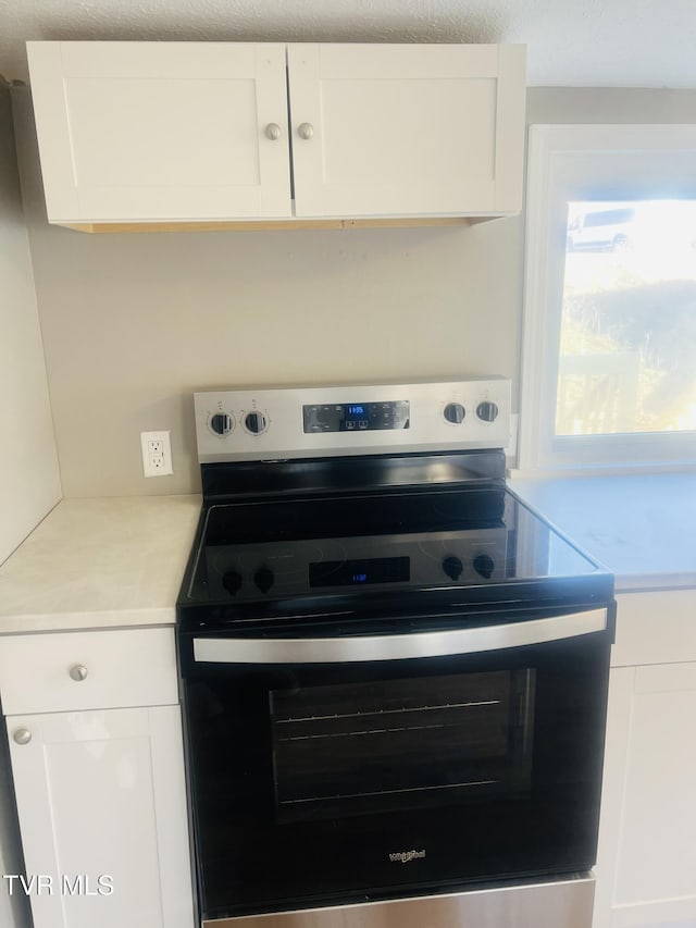 kitchen with stainless steel electric stove and white cabinets