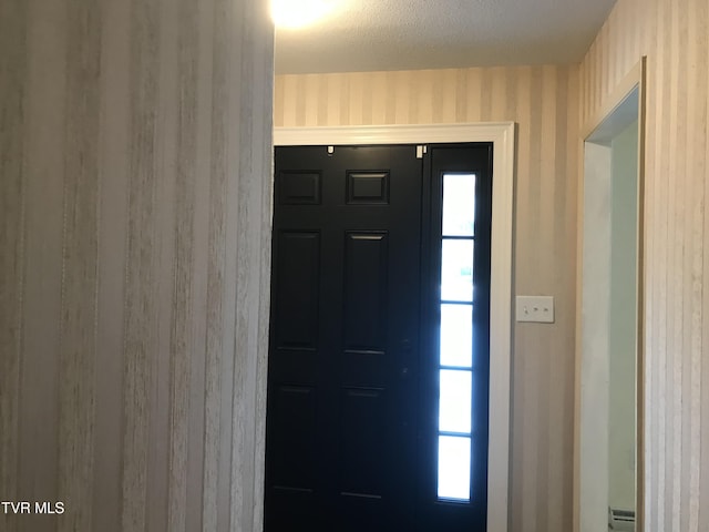 foyer entrance with wallpapered walls, a textured ceiling, a wealth of natural light, and a baseboard heating unit