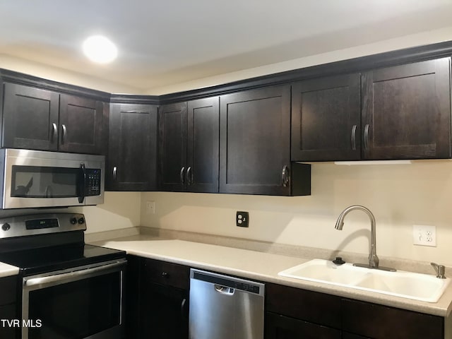 kitchen with appliances with stainless steel finishes, sink, and dark brown cabinetry