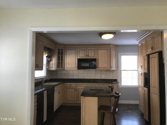 kitchen with black appliances, a kitchen island, tasteful backsplash, sink, and a breakfast bar area