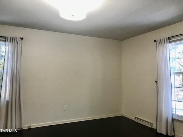 unfurnished room featuring a baseboard heating unit and baseboards