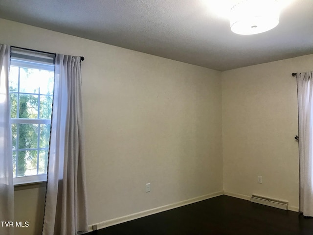 empty room with baseboards and dark wood-type flooring