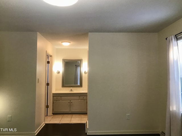 hall with light tile patterned floors, baseboards, and a sink