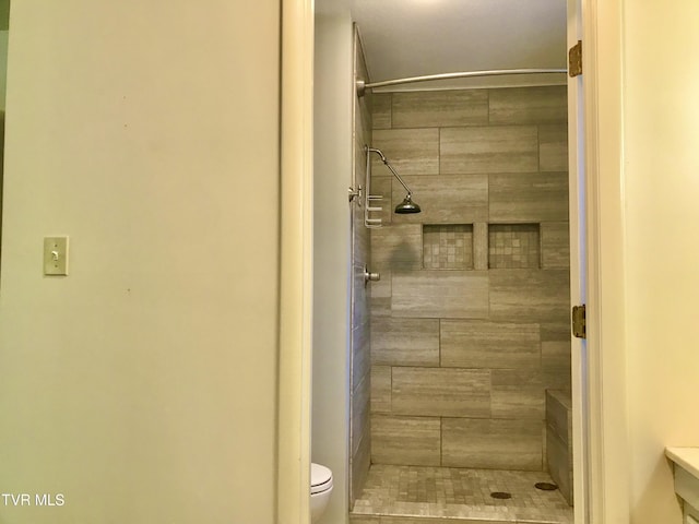 full bath with toilet and a tile shower