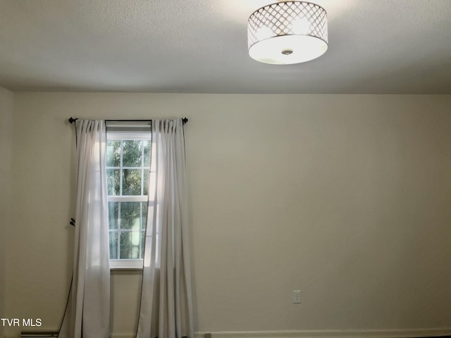 empty room with a textured ceiling and a healthy amount of sunlight