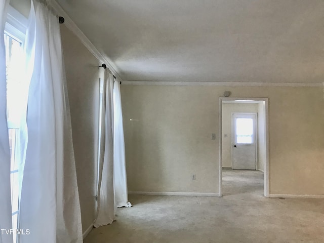 carpeted empty room featuring baseboards and crown molding