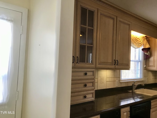 kitchen with dishwasher, dark countertops, glass insert cabinets, and a sink