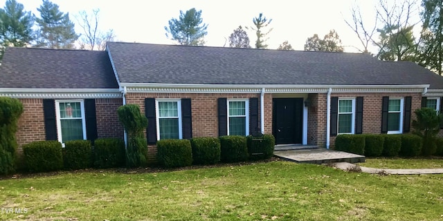 view of front of home with brick siding, a front lawn, and a shingled roof