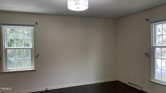 empty room with dark wood-style flooring, baseboards, and baseboard heating