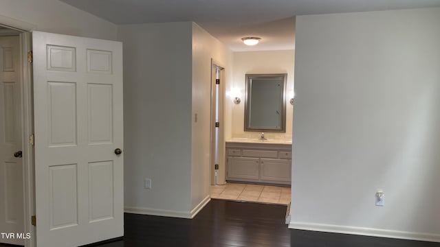 hallway with baseboards, a sink, and light wood finished floors