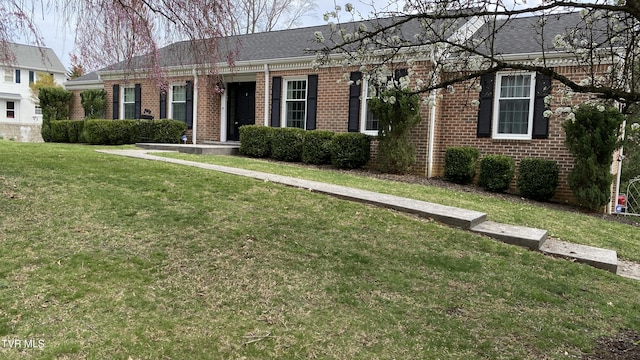 single story home featuring brick siding, a shingled roof, and a front yard