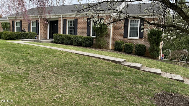 ranch-style house with brick siding, a front yard, and roof with shingles