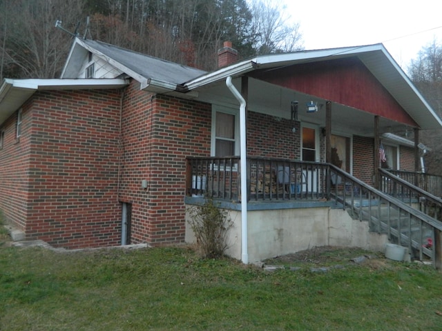 view of side of property with a lawn and covered porch