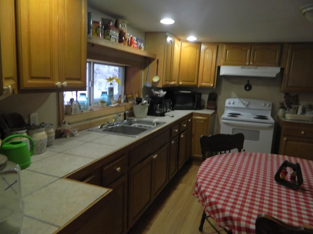 kitchen featuring sink, tile countertops, light hardwood / wood-style floors, and electric stove