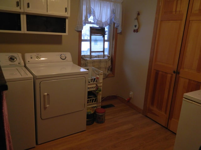 washroom featuring separate washer and dryer, cabinets, and light wood-type flooring