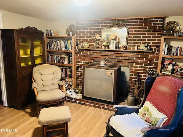 living area with light wood-type flooring and brick wall