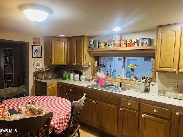 kitchen featuring tile counters, sink, and light hardwood / wood-style flooring